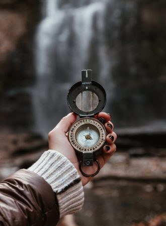 woman-checks-compass-at-waterfall